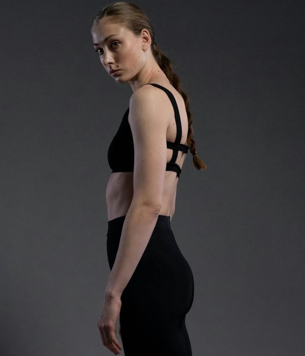 Woman in a calm, focused yoga pose against a dark, serene background.
